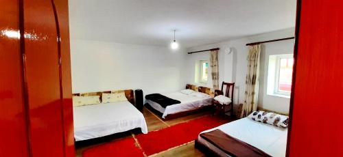 a hotel room with two beds and a red rug at Camping SuperPanorama in Kukës