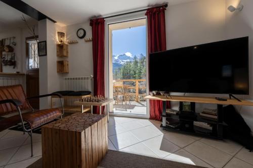 ein Wohnzimmer mit einem Flachbild-TV und einem großen Fenster in der Unterkunft Le Mas des Vigne - Vue exceptionnelle - Forêt in Uvernet