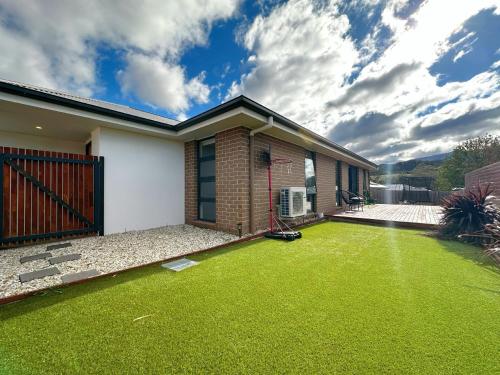a house with a yard with green grass at New Kingston Trampoline House in Kingston