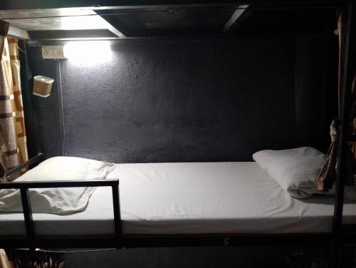 a bed in a room with a black wall at Bapuji Paying Guest Santacruz West in Mumbai