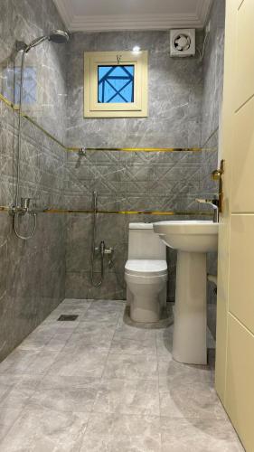 een badkamer met een toilet, een wastafel en een raam bij دانه القحطاني للوحدات السكنية in Tabuk