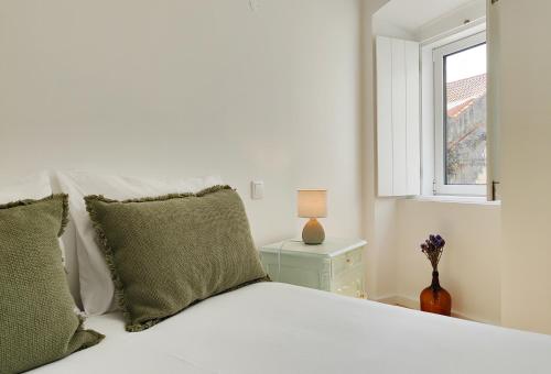 - un lit blanc avec des oreillers verts et une fenêtre dans l'établissement Casinha d`Santiago, à Santiago do Cacém
