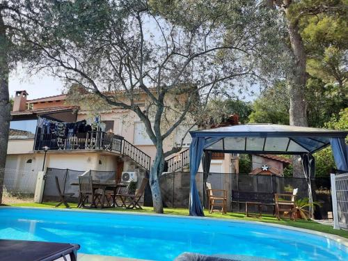 a pool with a gazebo next to a house at Villa climatisée piscine in Montpellier