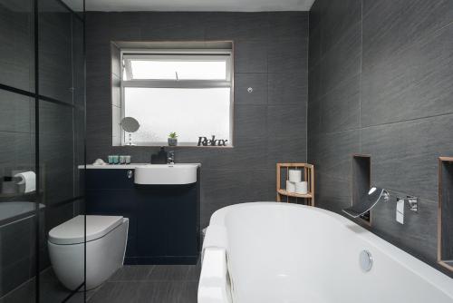 a bathroom with a white tub and a toilet and a window at Superb Beverley 3 Bedroom House with Private Parking and Garden - The Nicholson in Beverley