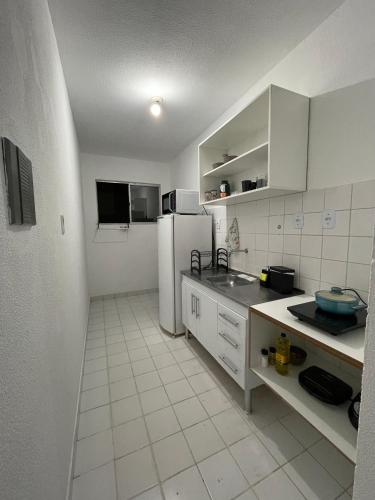  La cuisine est équipée de placards blancs et d'un réfrigérateur. dans l'établissement Apartamento aconchegante 2, à Jequié