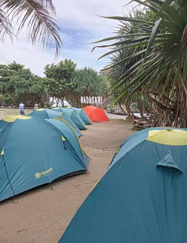 una fila de tiendas están alineadas en la playa en Madasari Outdoor Camping Hemat en Bulakbenda