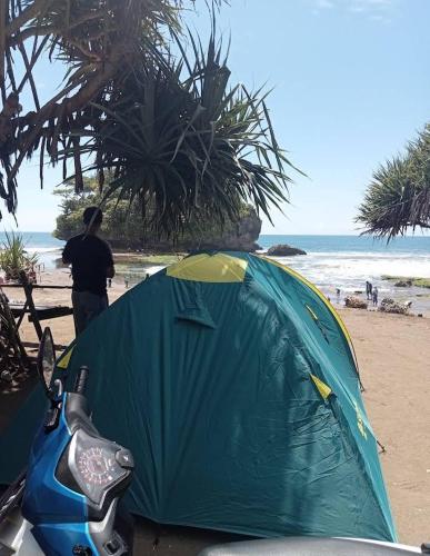 una persona de pie junto a una tienda en la playa en Madasari Outdoor Camping Hemat en Bulakbenda