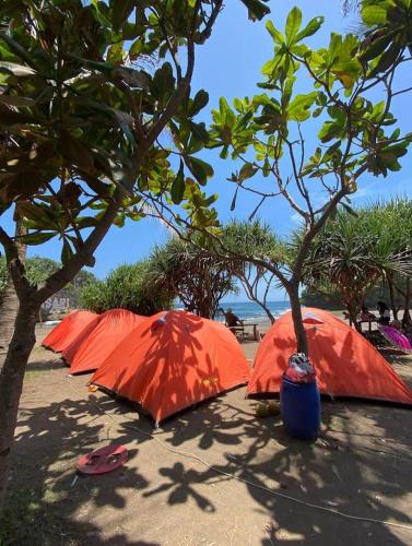 una fila de sombrillas naranjas sentadas en la playa en Madasari Outdoor Camping Hemat en Bulakbenda