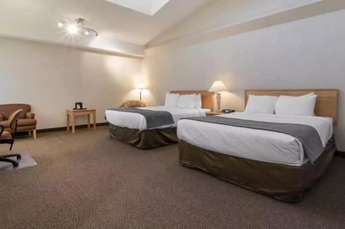 a hotel room with two beds and a chair at Flamingo Hotel in Medicine Hat