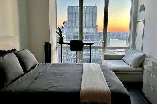 ein Schlafzimmer mit einem Bett und einem Sofa und einem großen Fenster in der Unterkunft Skyline vie, Luxury, Quiet 1br in New York