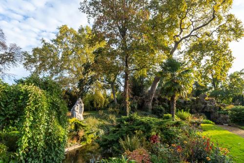 un jardin avec des arbres, des buissons et un étang dans l'établissement Hôtel de Berri Champs-Élysées, a Luxury Collection Hotel, à Paris