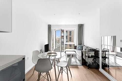 a white kitchen with a table and chairs in a room at Stylish Flat In Battersea Reach in London