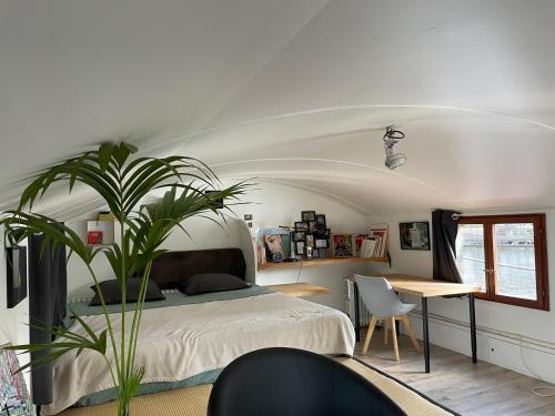 a bedroom with a bed and a table and a plant at Péniche le Sémaphore in Nantes