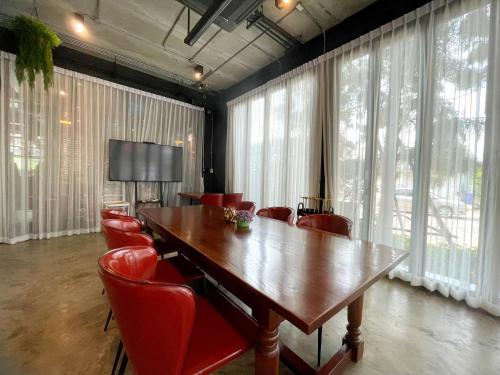 a conference room with a wooden table and red chairs at Nights in A Box in Ban Muang (1)