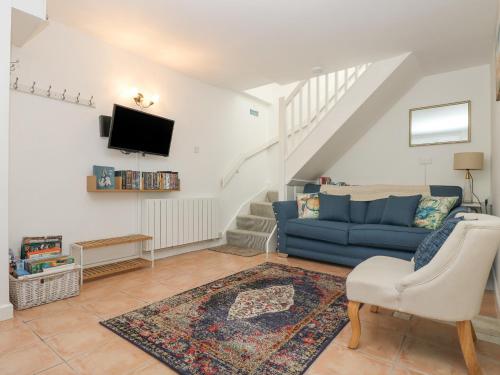 a living room with a blue couch and a tv at Longships in Penzance
