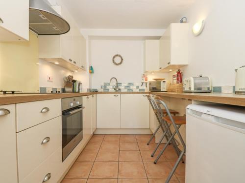 a kitchen with white cabinets and a counter top at Longships in Penzance