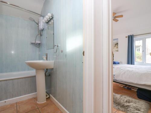 a bathroom with a sink and a bed in a room at Longships in Penzance