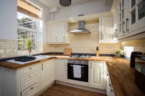 cocina con armarios blancos y fogones en West Beck House - Newcastle 6, en North Shields