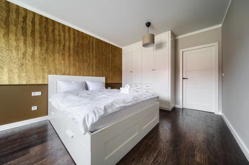 een slaapkamer met een wit bed en een houten vloer bij Wrocław Partynice Cosy Apartment in Wrocław