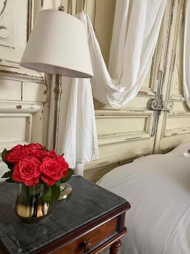 a table with a lamp and a vase of red roses at Chambres d'hôtes du château in Boulogne-sur-Mer