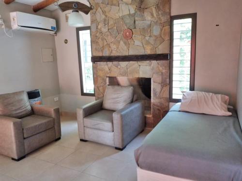 1 dormitorio con cama, silla y chimenea de piedra en Quality time en Luján de Cuyo