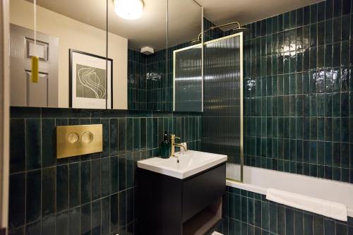 a green tiled bathroom with a sink and a mirror at The Twickenham Wonder - Lovely 1BDR Flat with Parking in Twickenham