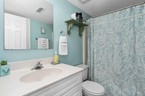 a bathroom with a sink and a shower curtain at Seaside Sunrise Sanctuary in Carolina Beach