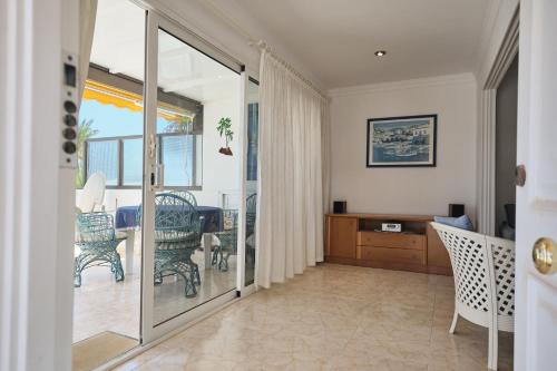 a living room with a sliding glass door with a table and chairs at Lovely Apartment in San Agustín: Steps Away from Playa Del Inglés and Maspalomas! in San Bartolomé de Tirajana