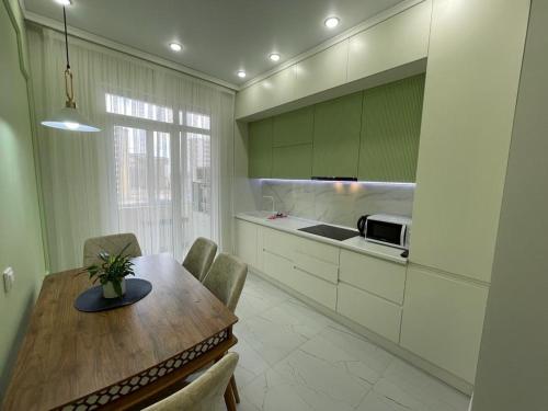 a kitchen with a wooden table with chairs and a counter at Нурсултан-сити in Astana
