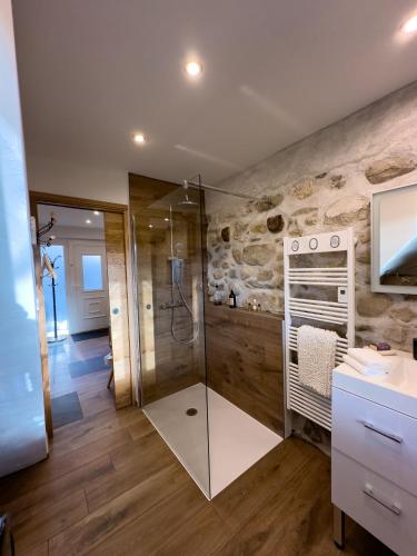 La salle de bains est pourvue d'une douche à l'italienne à côté d'un mur en pierre. dans l'établissement gite L'Ecrin, à Saint-Paul-sur-Yenne