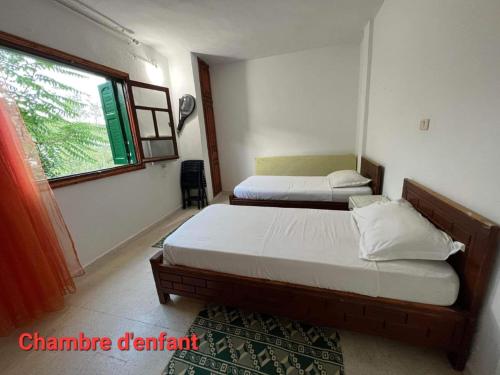 2 łóżka w małym pokoju z oknem w obiekcie Villa Bel air w mieście Aïn Draham