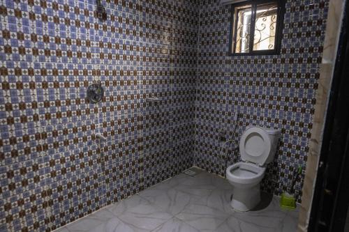 a tiled bathroom with a toilet and a window at VETTAS APARTMENT in Akure