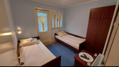 um pequeno quarto com 2 camas e uma janela em Domaćinstvo Jolović em Kraljevo