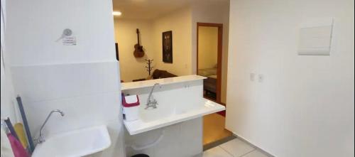 a white kitchen with a sink and a mirror at Apartamento Incrivel in Campo Grande