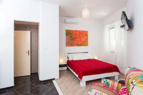 a bedroom with a red bed and a couch at Apartment Banjska in Dubrovnik