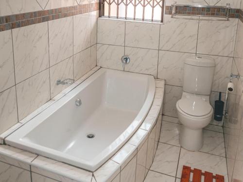 a bathroom with a white tub and a toilet at Khutso Boutique Hotel in Hazyview