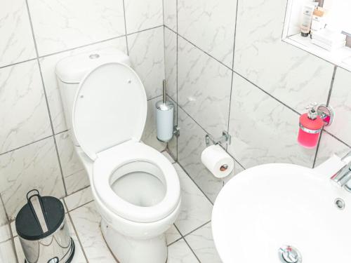 a white bathroom with a toilet and a sink at Khutso Boutique Hotel in Hazyview