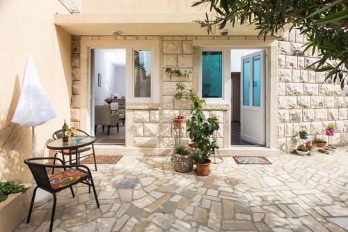 een patio met een tafel en stoelen en een stenen muur bij Apartment Banjska in Dubrovnik