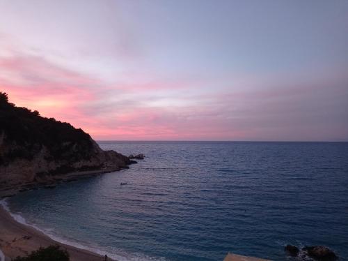 un tramonto sull'oceano con una spiaggia di Ostria a Ayios Nikitas