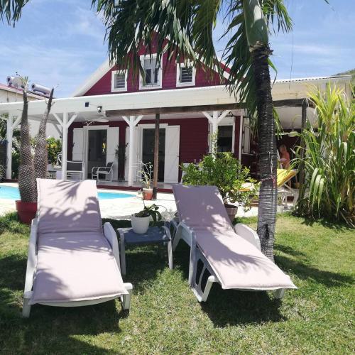 - deux chaises longues et une table en face d'une maison dans l'établissement Villa de caractère ,3 étoiles, avec piscine, jardin et plage à 200m, à La Trinité