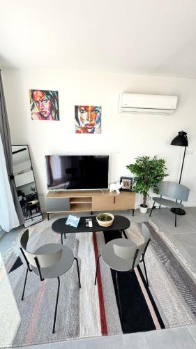 a living room with a table and chairs and a tv at Peyia Paradise Apt in Peyia