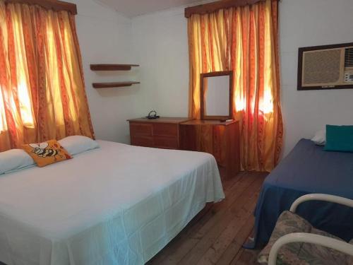 a bedroom with two beds and a mirror and curtains at Beautiful House in front of the beach at Masca, Omoa in Omoa