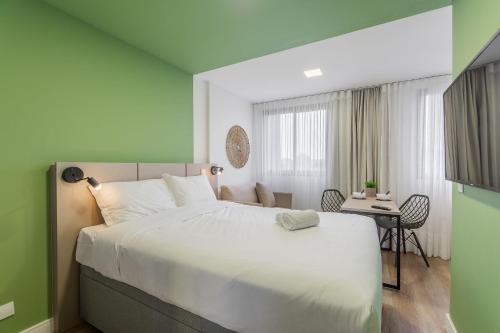 a bedroom with a large white bed and a desk at Easy Life Campus PUC by Xtay in Curitiba