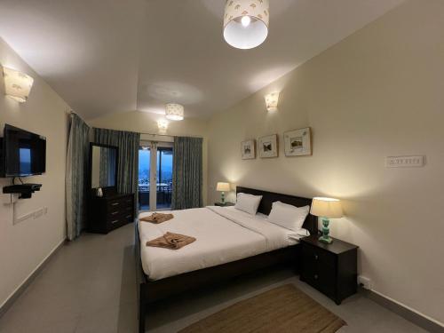 um quarto com uma cama grande e uma televisão em Sunset Villa em Coonoor