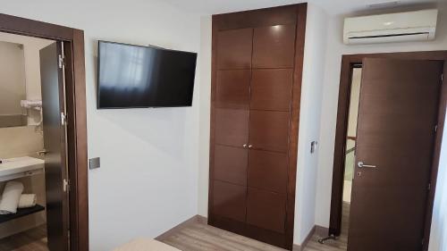 1 dormitorio con TV de pantalla plana en la pared en Hotel Boutique Aroma de Mar, en Chiclana de la Frontera