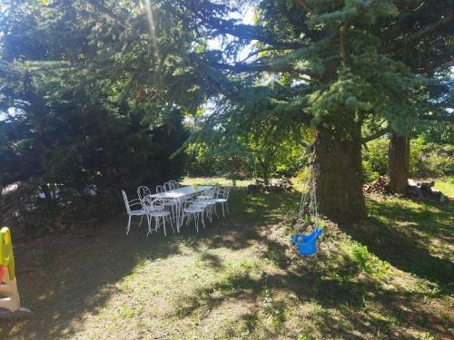 einen Tisch und Stühle unter einem Baum im Hof in der Unterkunft la Villa Charme et Confort in Chamaret