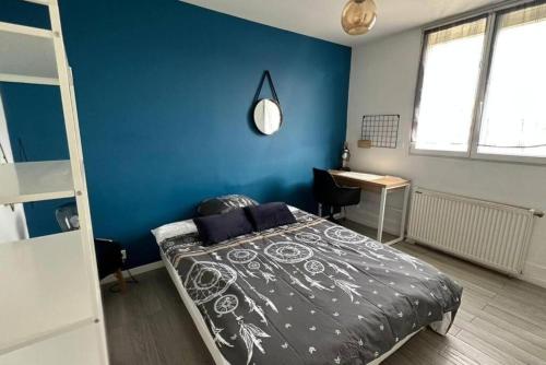 - une chambre avec un lit et un mur bleu dans l'établissement Joli appartement près de Rouen, à Le Petit-Quevilly