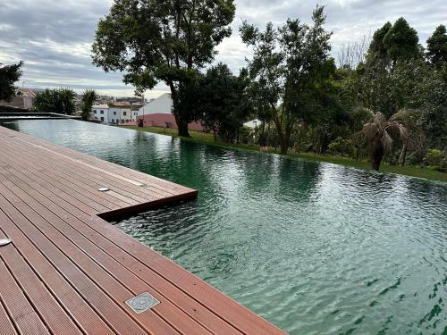 una gran piscina de agua con terraza de madera en Solar dos Cantos Botanic House & Garden, en Ponta Delgada
