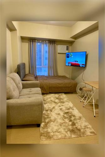 a living room with a couch and a flat screen tv at AVIDA ATRIA TOWER 3 Unit 3-320 in Iloilo City