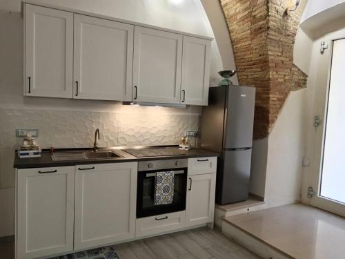 una cucina con armadi bianchi e frigorifero in acciaio inossidabile di GiuattyHomeHoliday Termoli a Termoli